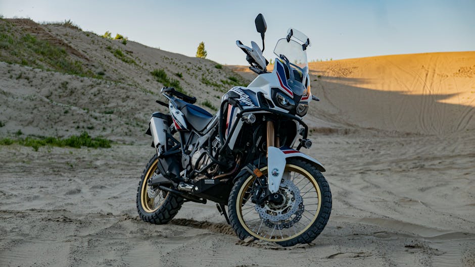 A rugged adventure motorcycle parked on expansive desert sand dunes