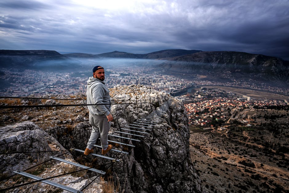 Man looks back while walking on narrow mountain trail above Mostar
